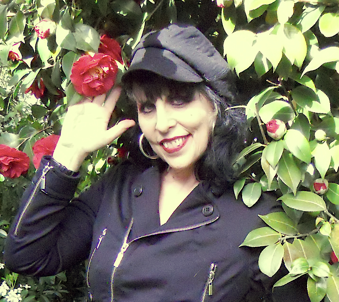 a woman in a black hat and black jacket holding a red flower