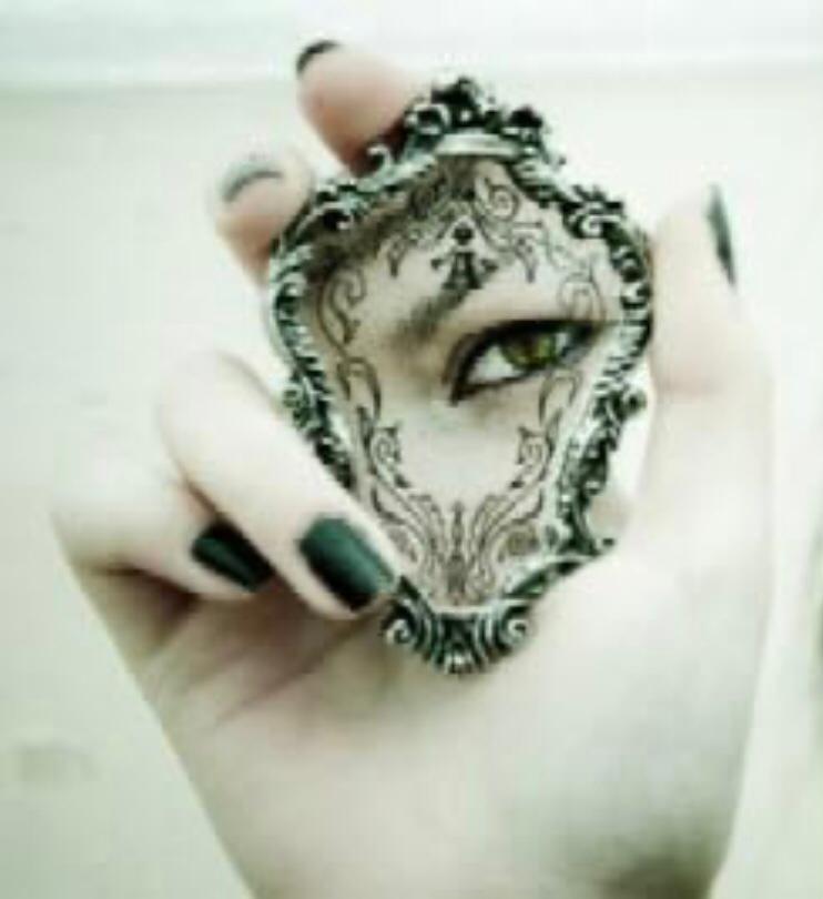 a hand holding a mirror with a hand painted eye