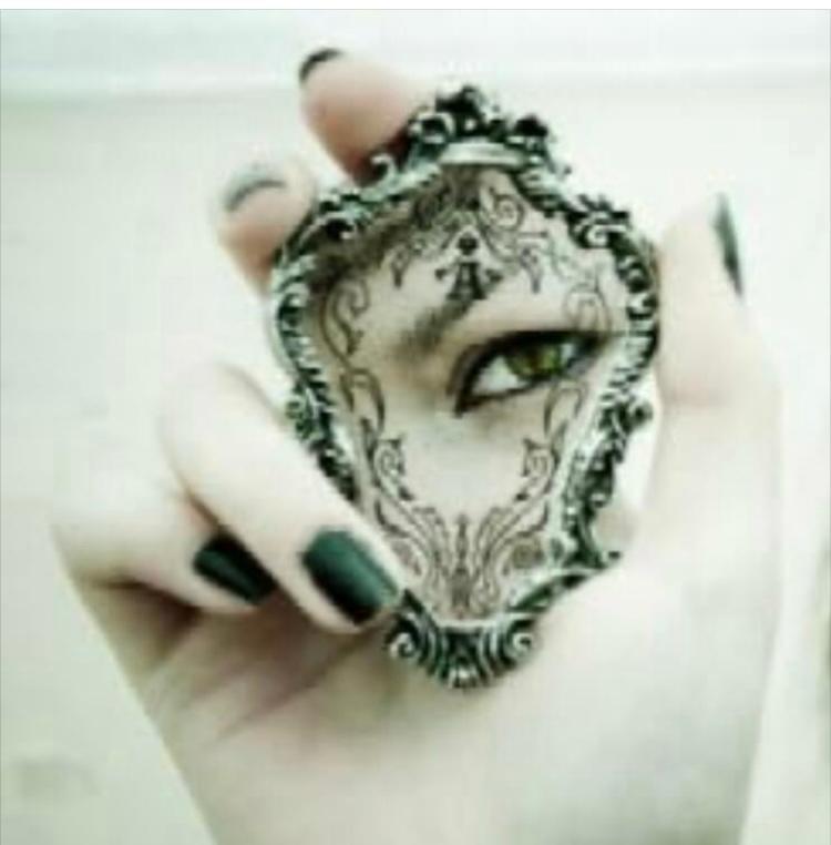 a hand holding a mirror with a human eye