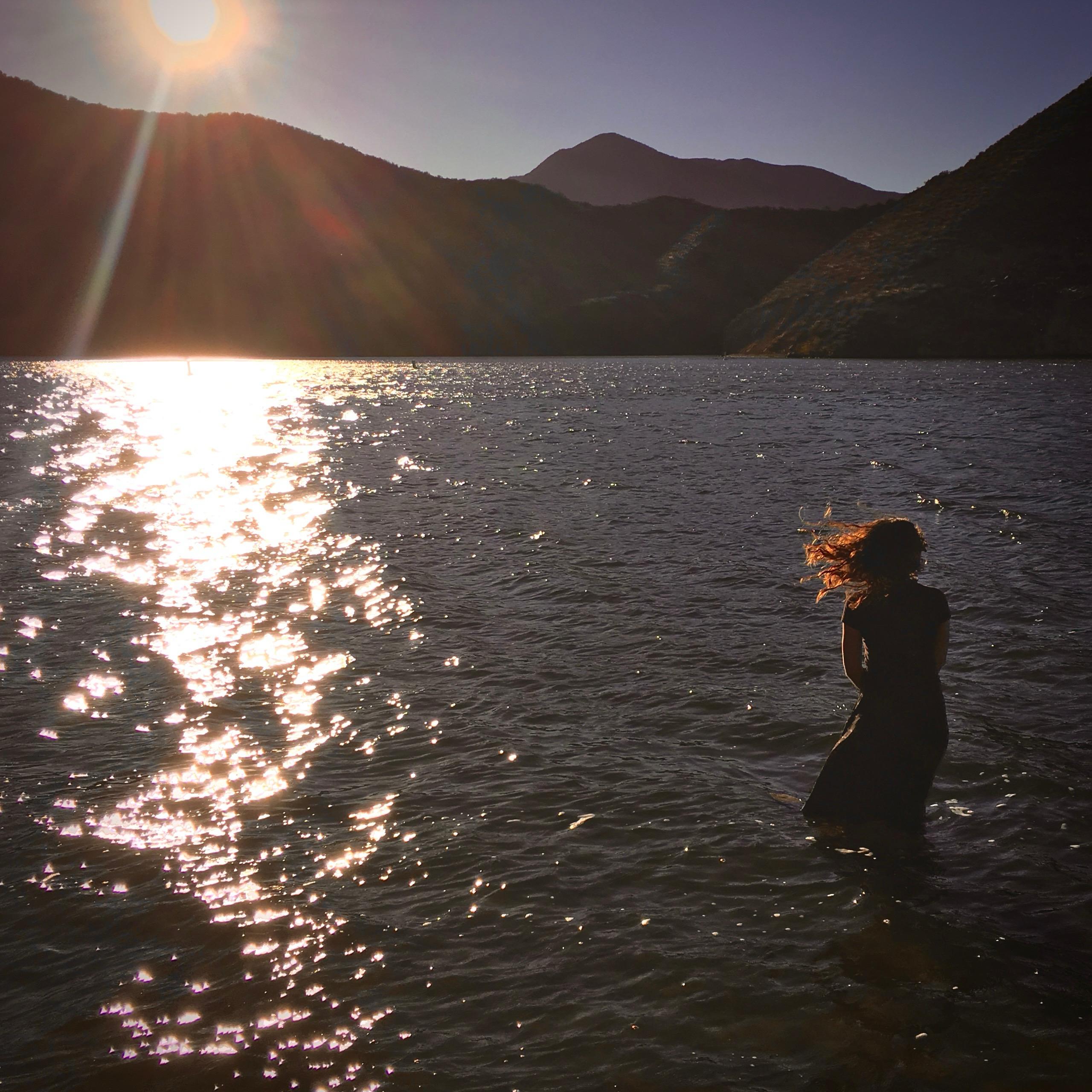 A woman standing in water with her hair blowing in the wind