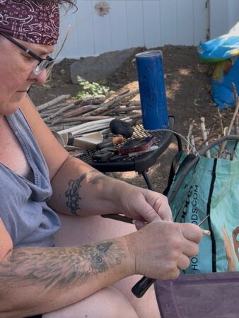 A woman sitting outside with a blue can and a blue bag