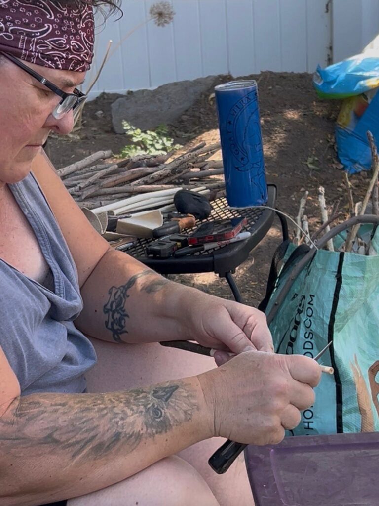 A woman sitting outside with a blue can and a blue bag