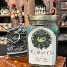 A glass jar with a green candle on a wooden surface