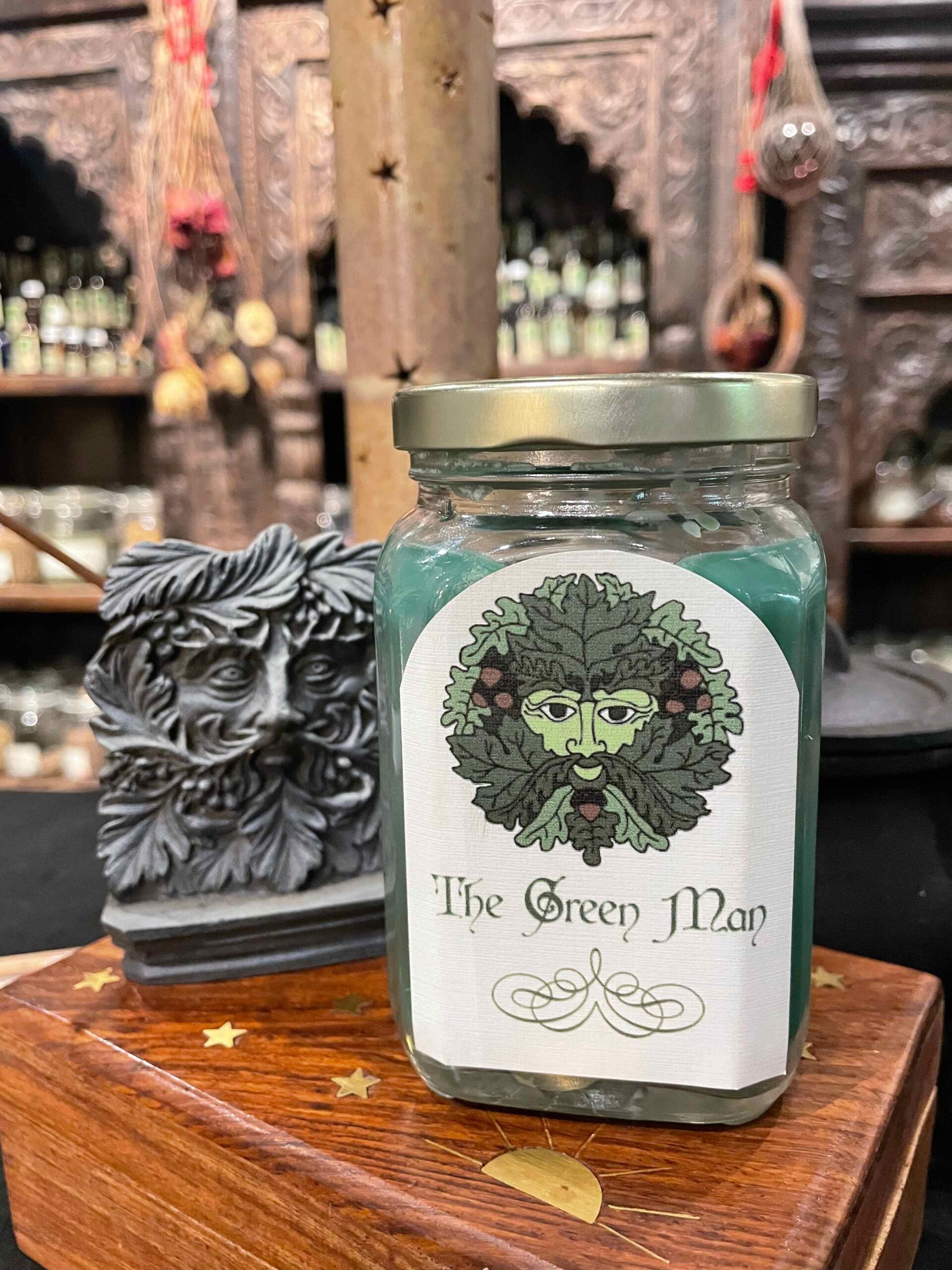 A glass jar with a green candle on a wooden surface